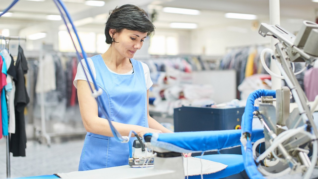 Textile Dienste: Arbeiterin bügelt Kleidung 