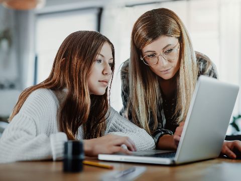 Mutter und Tochter schauen gemeinsam auf einen Laptop