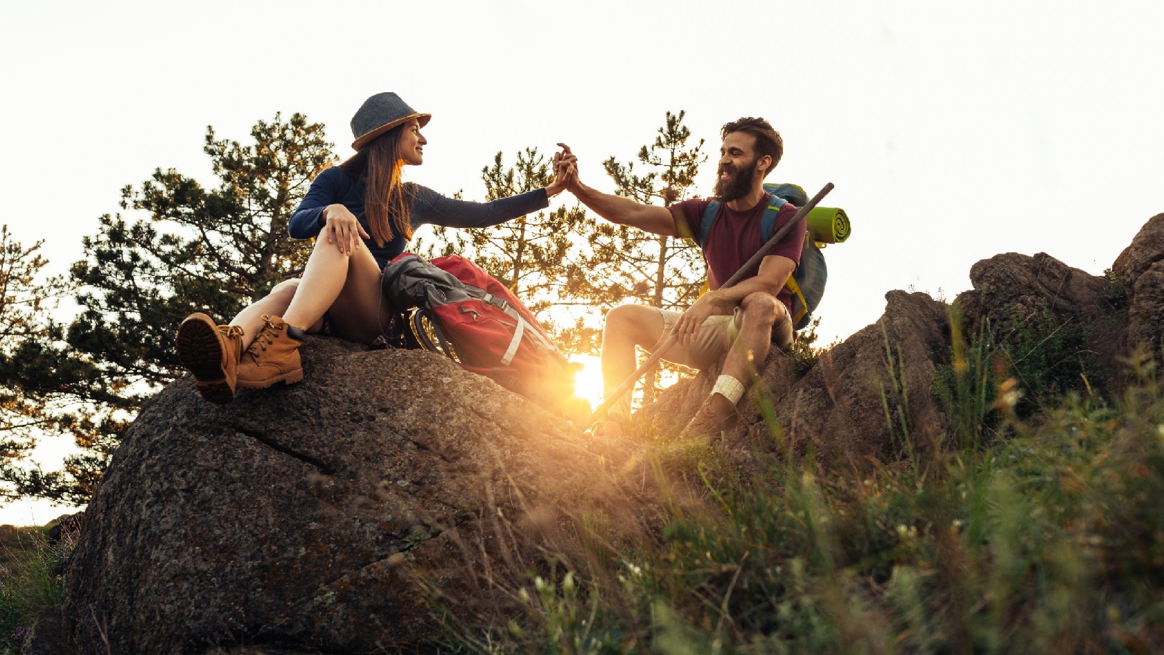 Wanderpaar sitzt vor Sonnenuntergang auf Felsgipfel