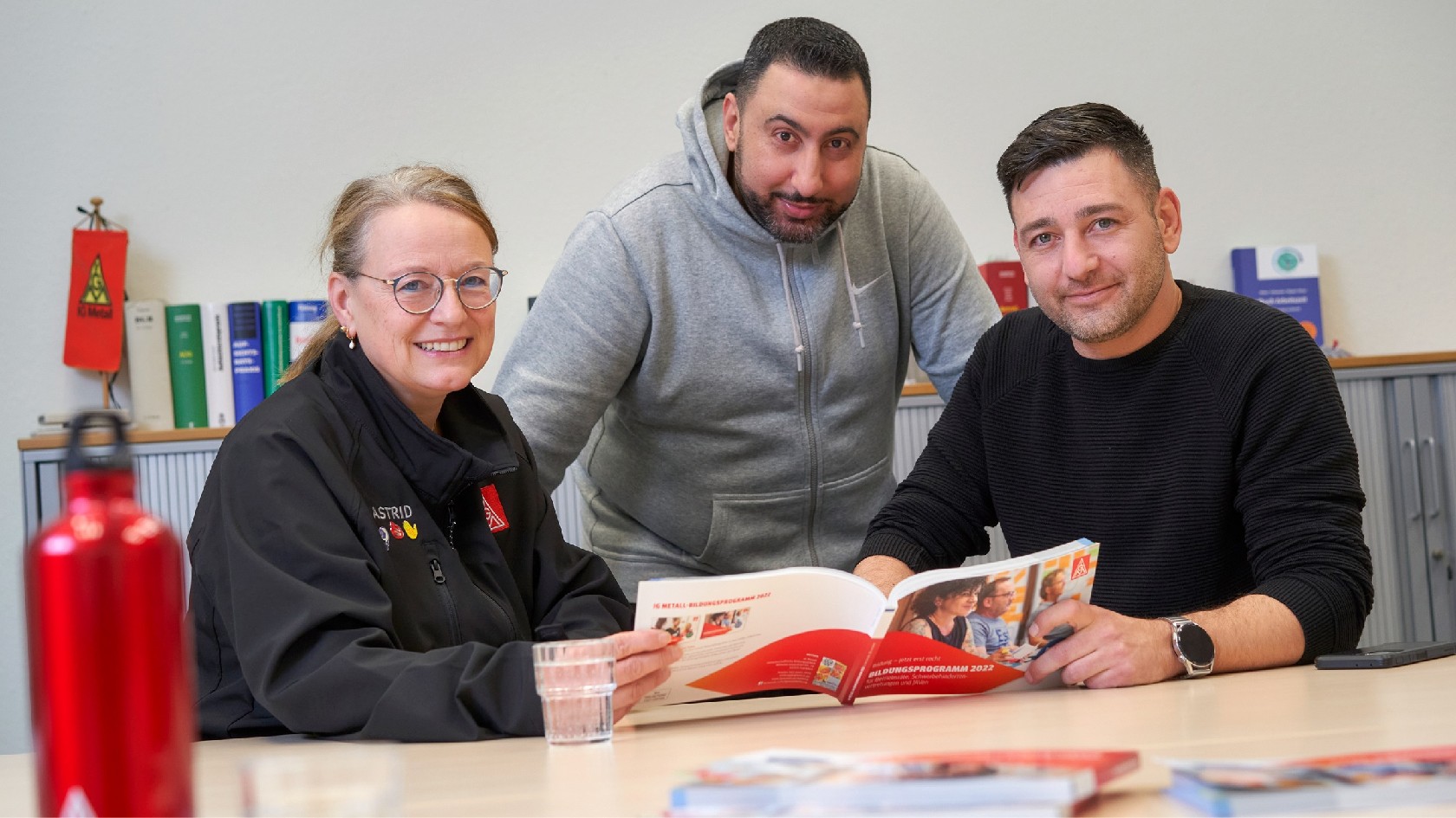 Drei Betriebsratsmitglieder blättern gemeinsam im neuen Bildungsprogramm der IG Metall