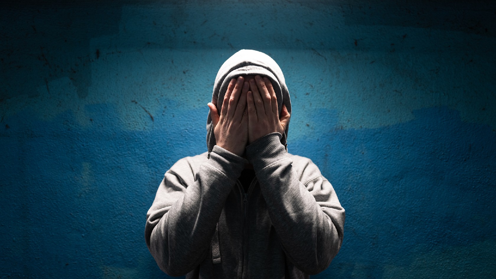 Depressiver Mann mit Händen über Gesicht in Verzweiflung