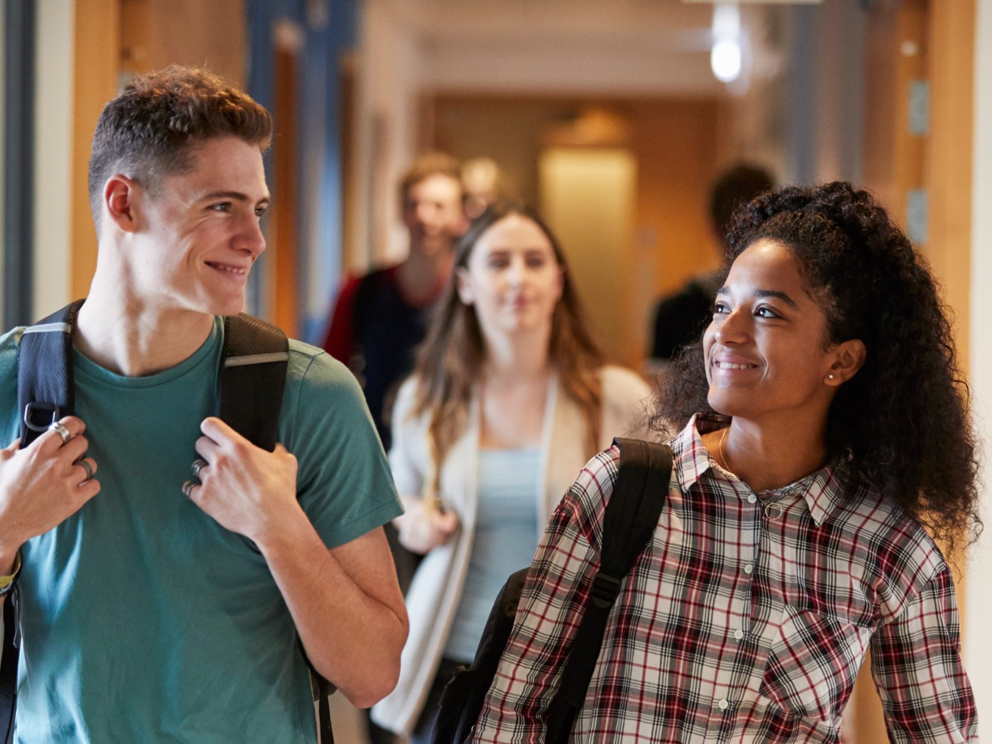 Eine Studentin und ein Student gehen gemeinsam über einen Korridor in einem Universitätsgebäude.