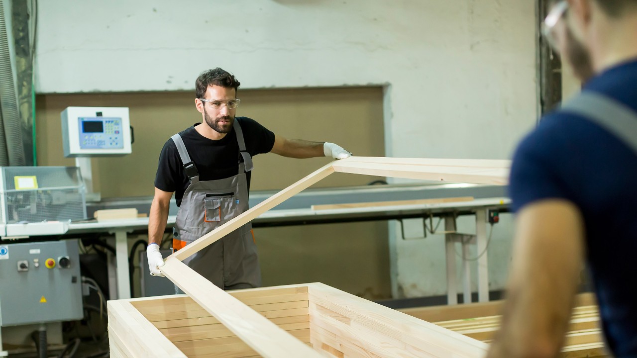Junge Männer arbeiten in einer Fabrik zur Möbelherstellung.